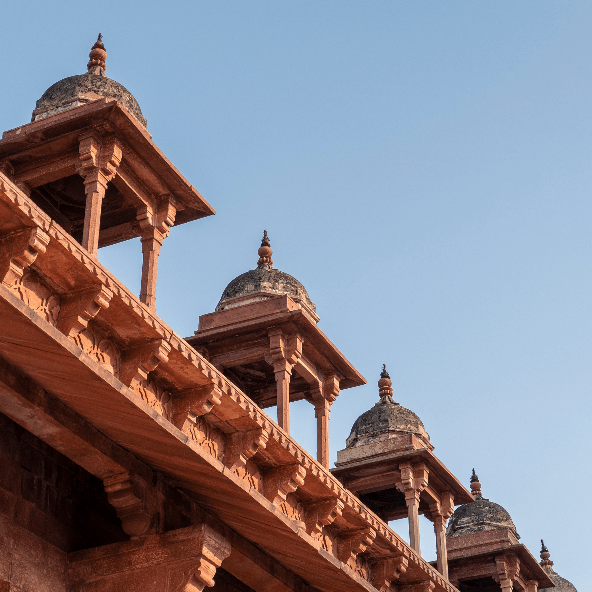 Red sandstone domed pavilions against a blue sky
